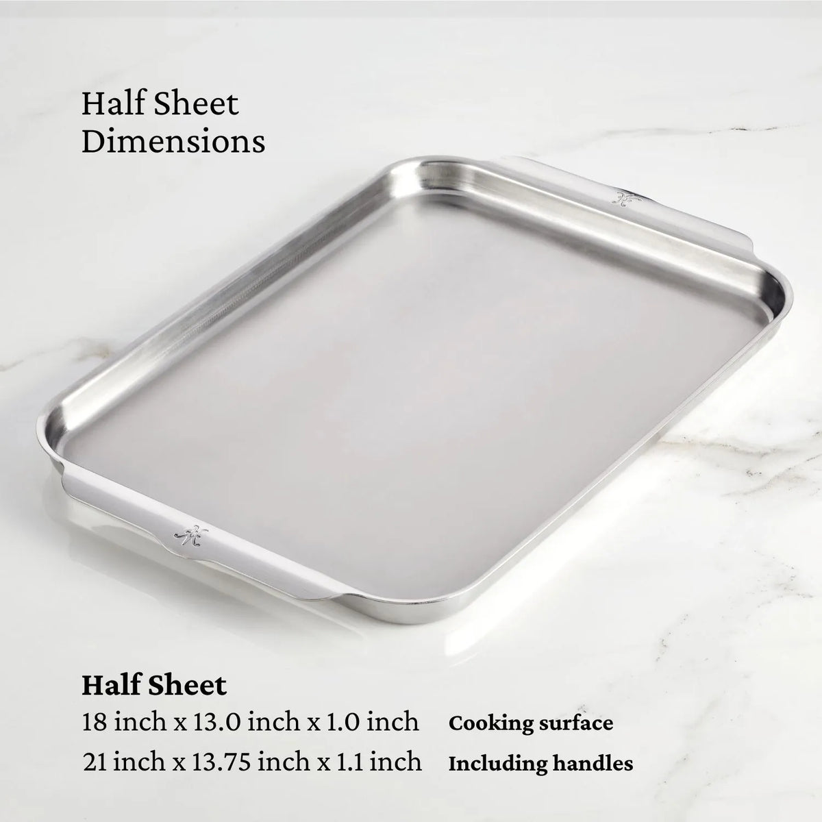 The Hestan OvenBond Tri-ply Half Sheet Pan & Rack, 13-in x 18-in, is shown on a marble surface. Dimensions: 18 x 13 x 1 in (cooking surface), 21 x 13.75 x 1.1 in (with handles)—a versatile roasting sheet pan.