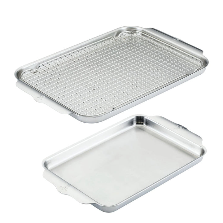 The OvenBond Tri-ply 3-Piece Set by Hestan Provisions includes two stainless steel sheet pans, with one featuring a grid-style wire rack and the other having a smooth surface and raised edges. Both warp-resistant pans have side handles for easy handling.