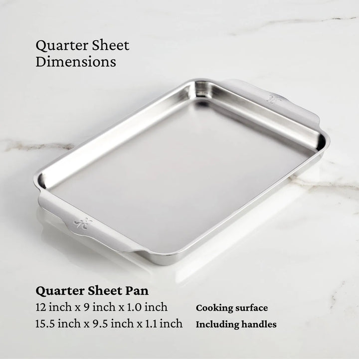 The OvenBond Tri-ply sheet pan by Hestan Provisions, with stainless steel and an aluminum core, is displayed on marble. Warp-resistant, its cooking area is 12x9x1 inches; overall dimensions with handles are 15.5x9.5x1.1 inches from the 3-piece set.