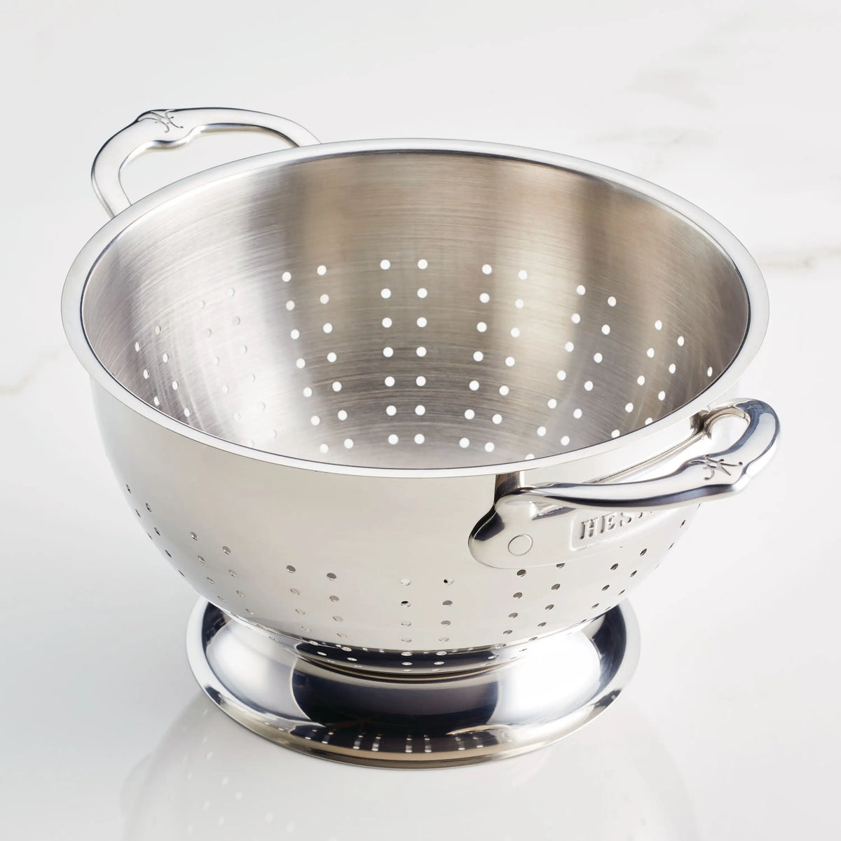 The Hestan Provisions Stainless Steel Colander features two handles, multiple small holes for superior drainage, a wide base, shiny finish, and is dishwasher safe for easy cleaning.