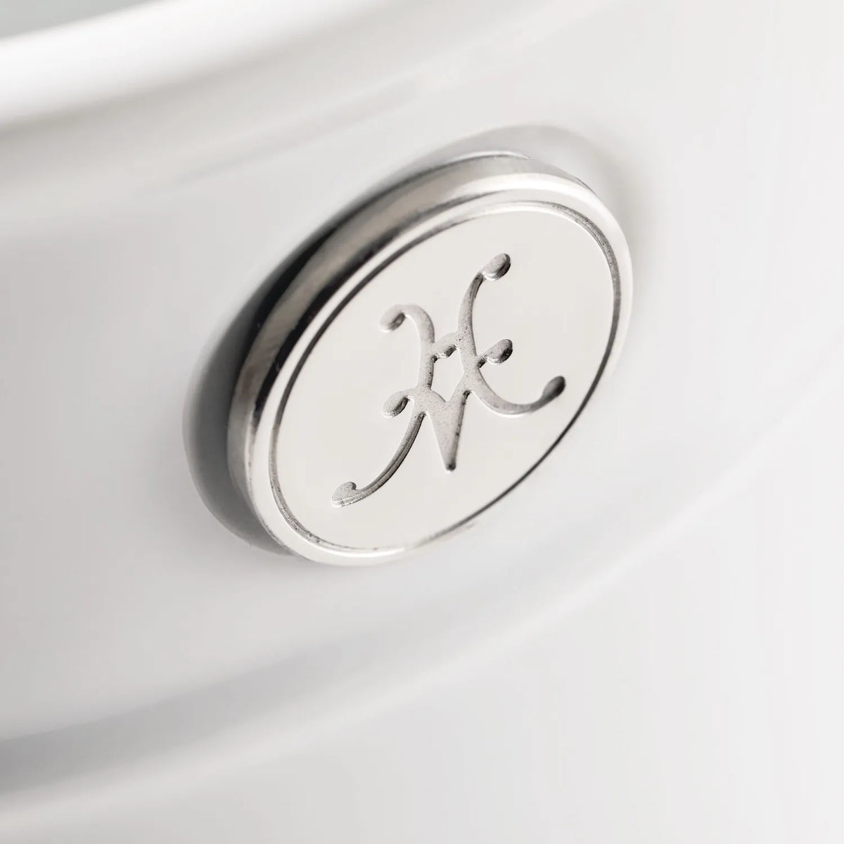 Close-up of a silver and white emblem featuring an intertwined H and F design on a smooth surface. Crafted from stainless steel with a raised metallic edge, the emblem embodies the quality synonymous with Hestan Provisions Deluxe Chefs Tool Set, 6-piece.