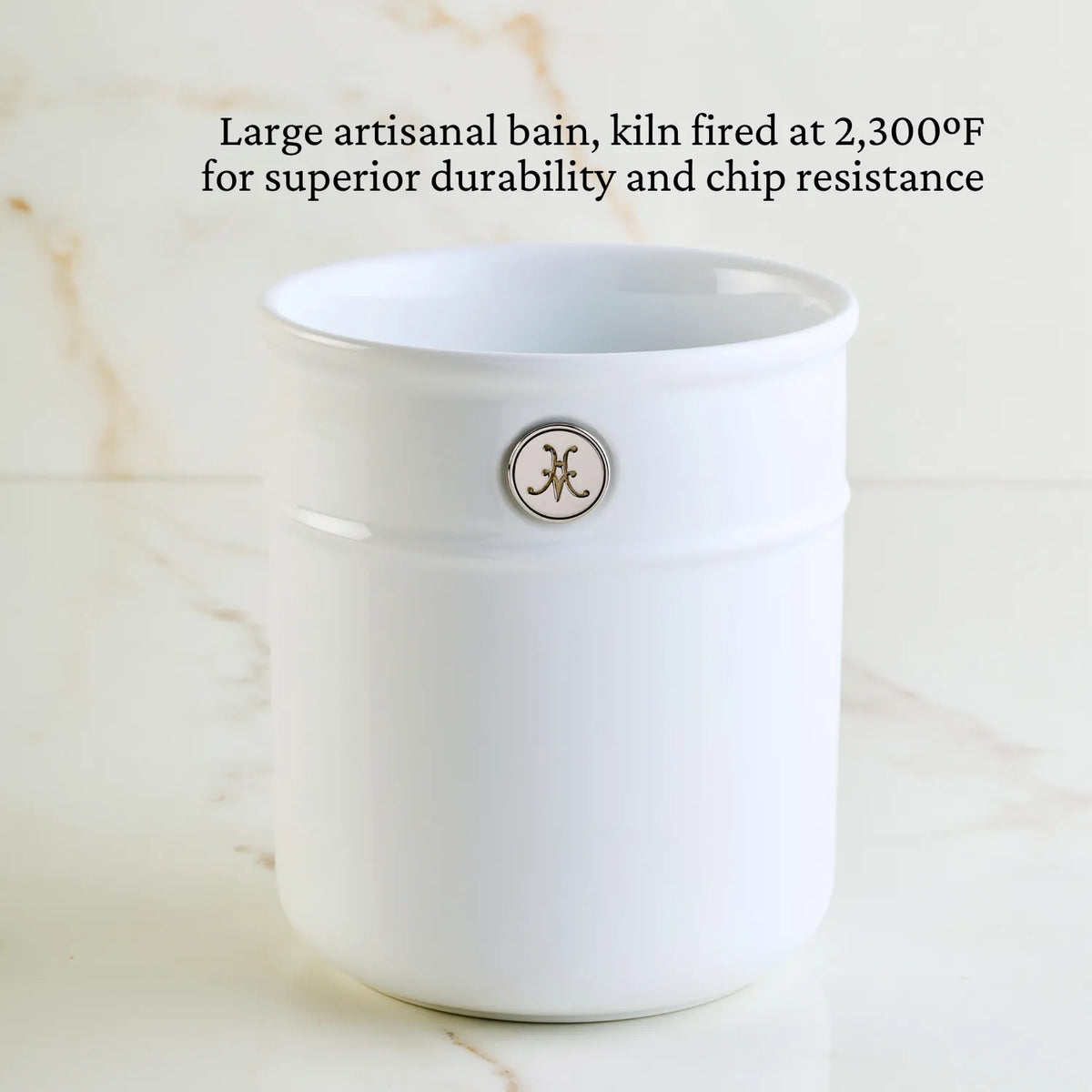 A white ceramic container sits on marble, featuring a small circular logo. Text above: Large artisanal bain, kiln fired at 2,300°F for exceptional durability and chip resistance. Ideal for Michelin-starred chefs seeking top-tier quality in Hestan Provisions Ultimate Chefs Tool Set, 8-piece.