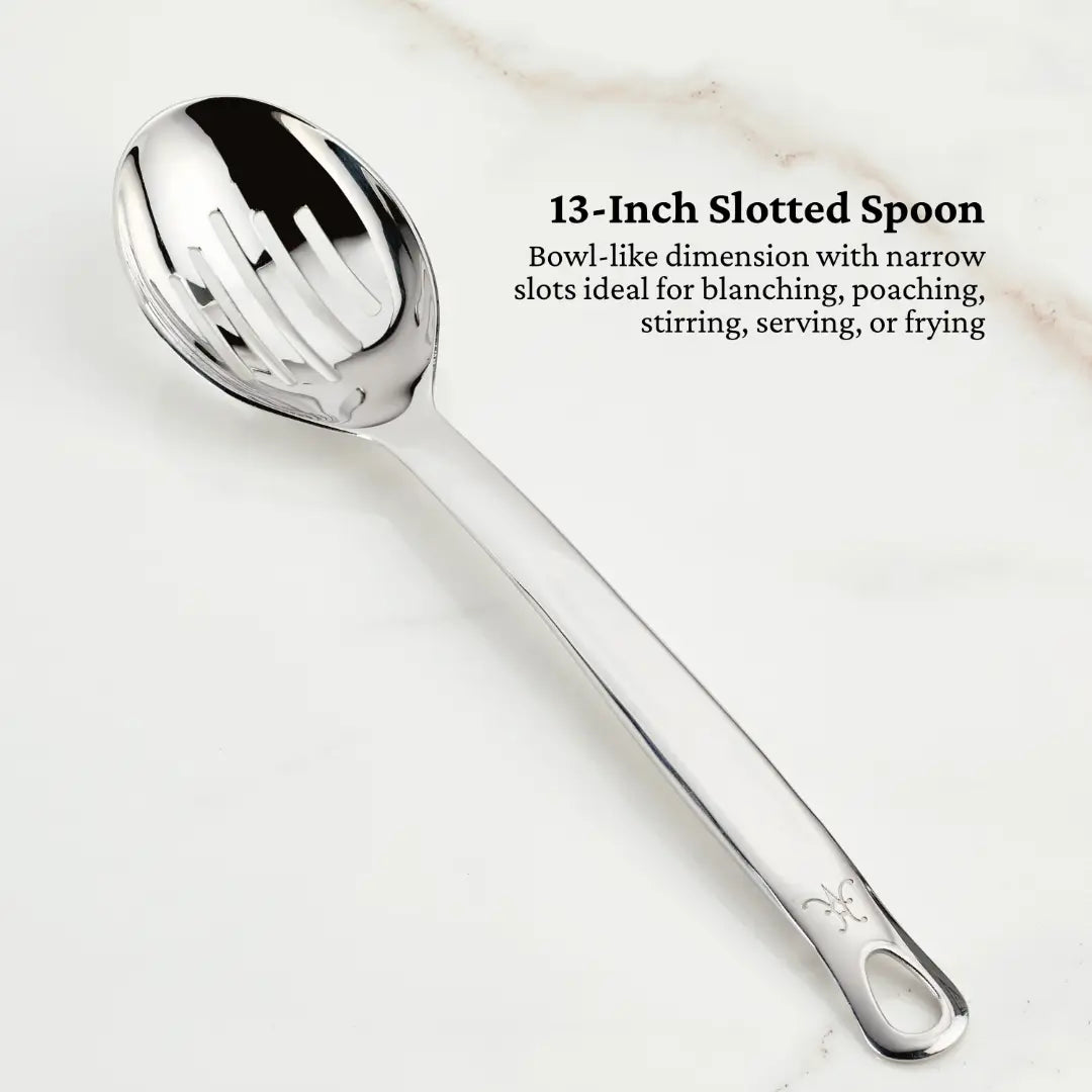 Part of the Ultimate Chefs Tool Set by Hestan Provisions, a 13-inch slotted spoon with a shiny 18/10 stainless steel finish lies diagonally on a white surface. Its narrow slots make it ideal for blanching, poaching, stirring, serving, or frying—perfect for any Michelin-starred kitchen.