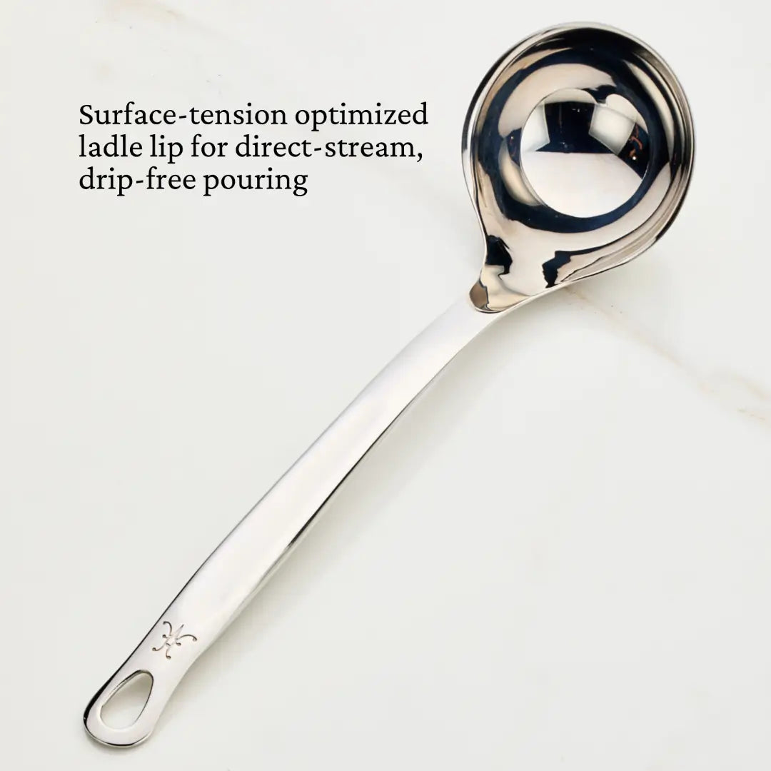 The Hestan Provisions 5-ounce ladle, featuring a polished stainless steel finish and long handle with a hole for hanging, is shown on a light background. Designed for drip-free pouring, its features are highlighted in the image as an essential Chef’s tool.