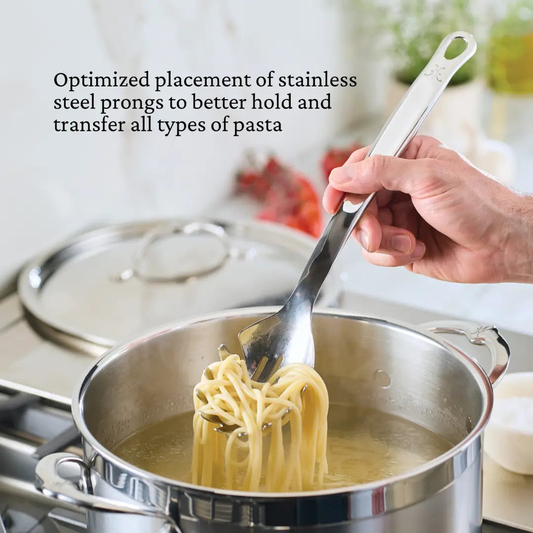 A person is using a Hestan Provisions 13-inch pasta fork to lift spaghetti from a boiling pot, with the lid beside it. Text highlights prong placement optimization for better pasta handling, showcasing precision in chefs tools.