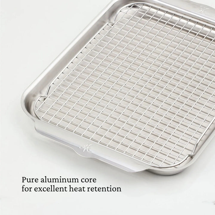 The Hestan Provisions OvenBond Tri-ply Medium Sheet Pan with Rack is displayed on a light surface. The pan features a pure aluminum core for excellent heat retention, raised edges, and a shiny finish, making it oven-safe for all your baking needs.