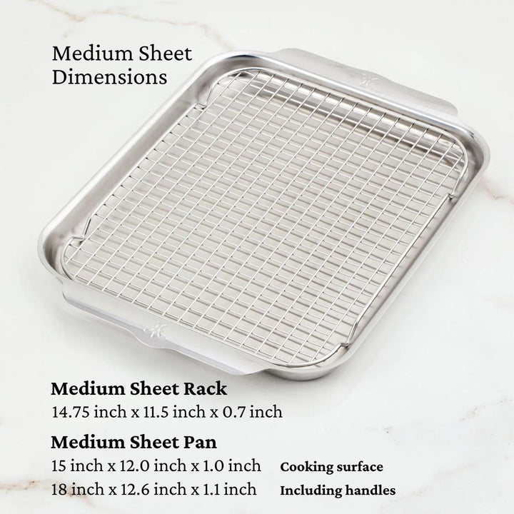 A Hestan OvenBond Tri-Ply Medium Sheet Pan & Rack, 12" x 15", rests on light marble. The rack is 14.75" x 11.5" x 0.7". The pan’s cooking surface is 15" x 12" x 1", or 18" x 12.6" x 1.1" with handles attached.