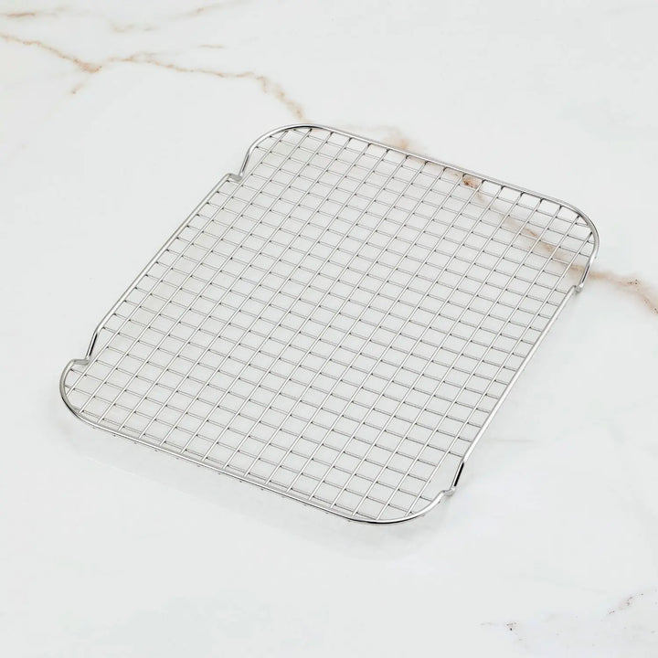 The Hestan OvenBond Tri-Ply Medium Sheet Pan & Rack (12-in x 15-in) features a rectangular grid-patterned rack on a white marble surface with light brown veins, perfectly complementing its premium stainless steel design.