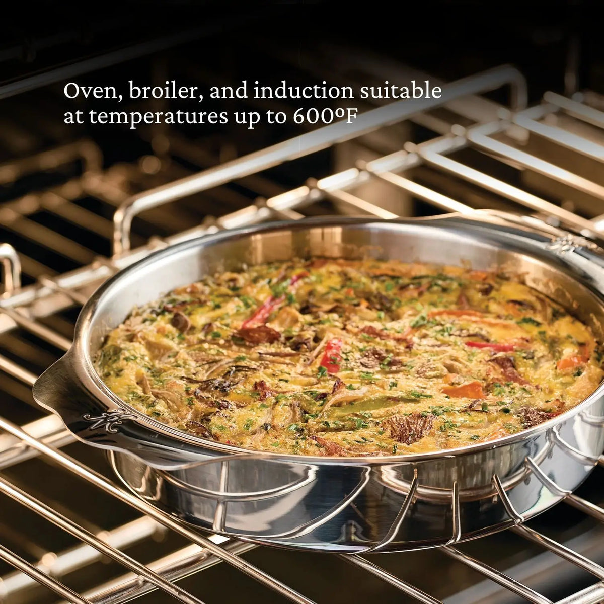 A 9-inch OvenBond Round Baker by Hestan Provisions holds a baked vegetable and herb dish on an oven rack. Text on the image states, Oven, broiler safe, and induction suitable at temperatures up to 600°F.