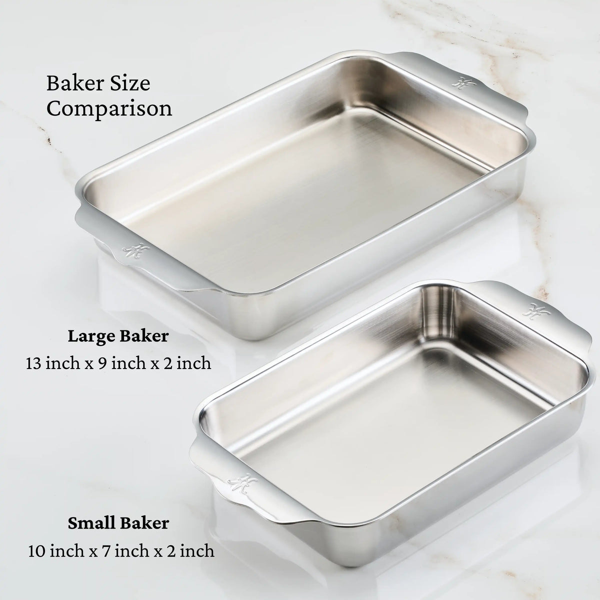 Two rectangular baking dishes from Hestan Provisions are on a white marble surface. The tri-ply clad stainless steel Large Baker measures 13x9x2 inches, and the OvenBond Tri-ply Small Rectangular Baker is 10x7x2 inches. Both are oven-safe.