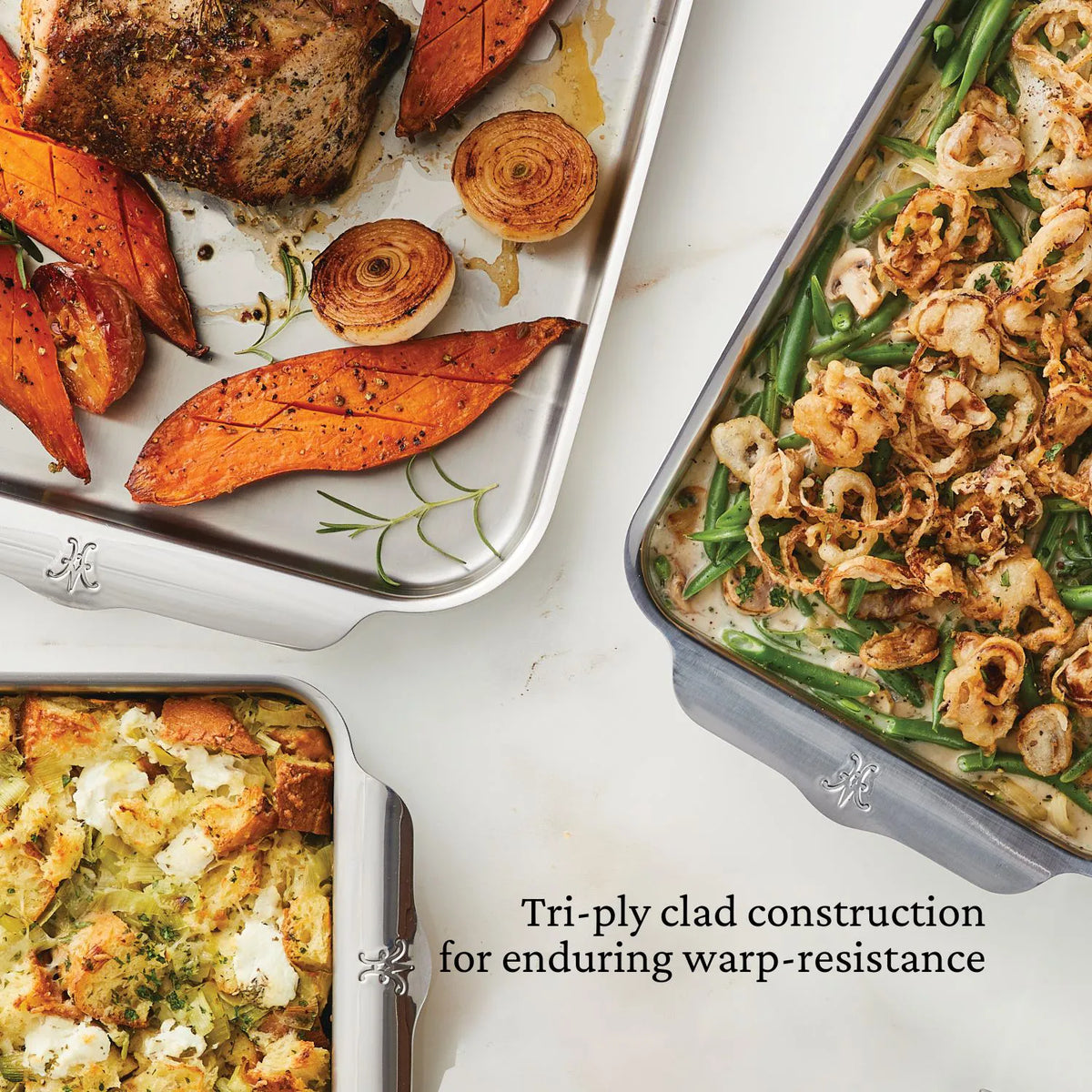 Three stainless steel dishes in the Hestan Provisions OvenBond Tri-ply Gourmet Essentials Set display roasted meat with veggies, green beans with crispy onions, and baked pasta. Text reads, Tri-ply clad construction for enduring warp-resistance, emphasizing this award-winning kitchen gear.