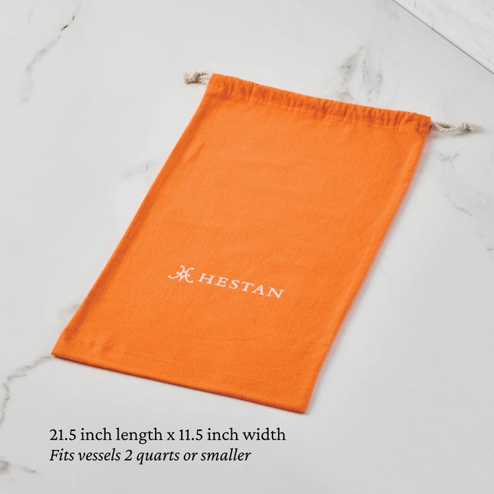 A Flannel Cookware Storage Bag by Accessories lays flat on marble. This orange drawstring bag fits cookware up to 2 quarts, measures 21.5" x 11.5", and is ideal for protecting and storing your kitchen vessels.