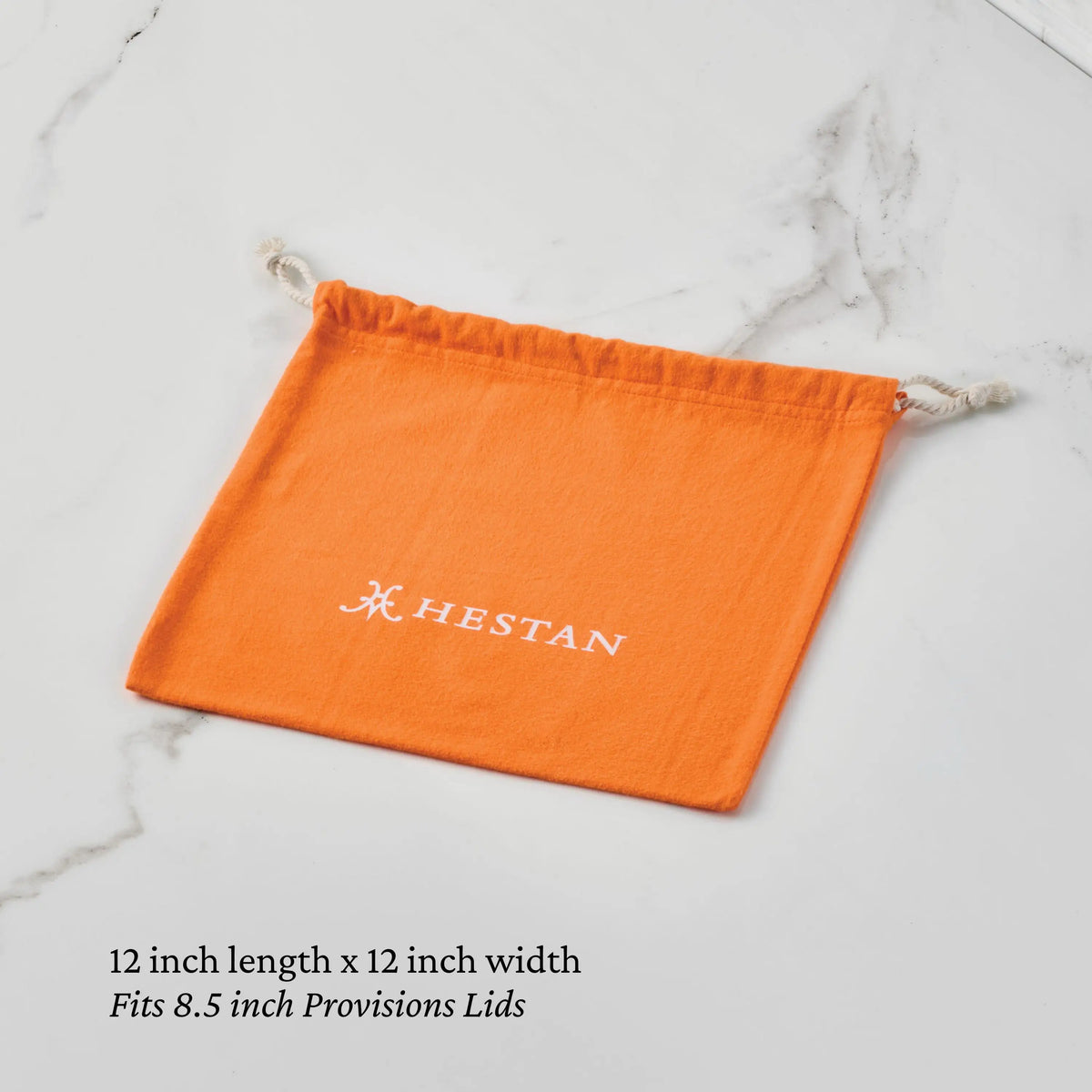 A 12 x 12 inch orange Accessories Flannel Lid Storage Bag with white logo, shown on marble. Ideal for storing 8.5 inch Provisions Lids and other stainless steel lids.