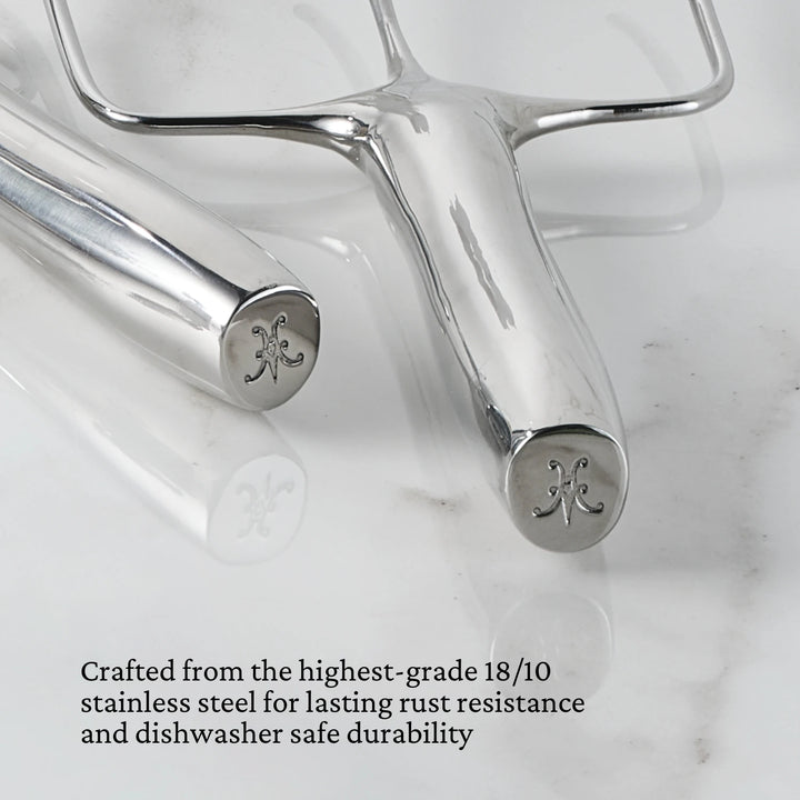 Two Hestan Provisions® Stainless Steel Carving Forks, Set of 2, with engraved handles rest on a white marble surface. Crafted from premium 18/10 stainless steel with a polished finish, these utensils are highlighted by text below for their exceptional rust resistance and dishwasher-safe durability.