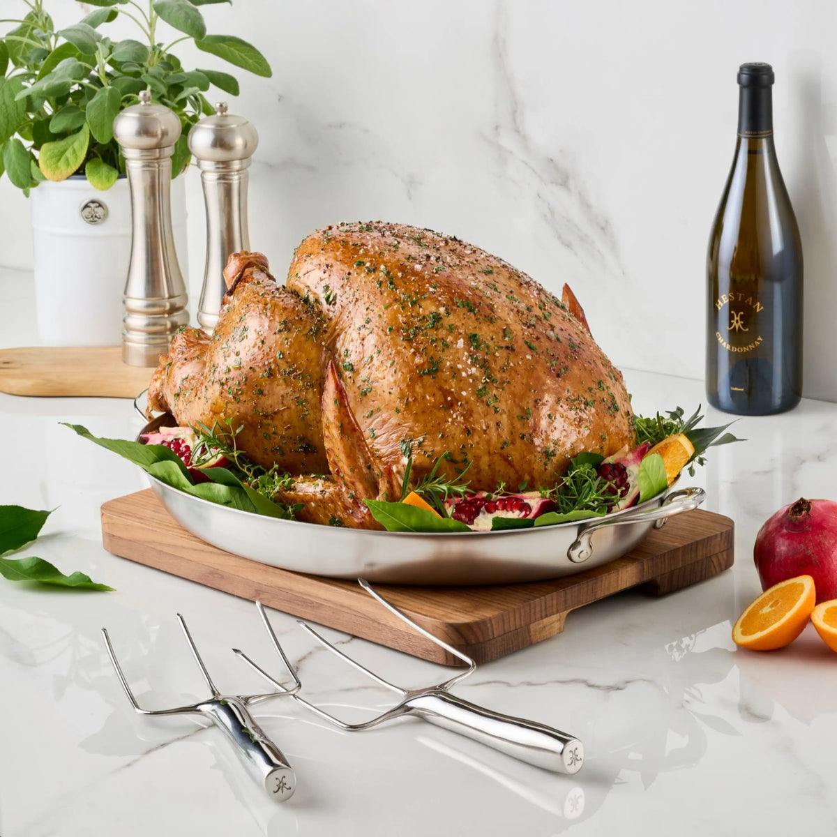 Two Hestan Provisions® Stainless Steel Carving Forks, Set of 2, resting on a marble surface in front of a roasted turkey on a metal platter.