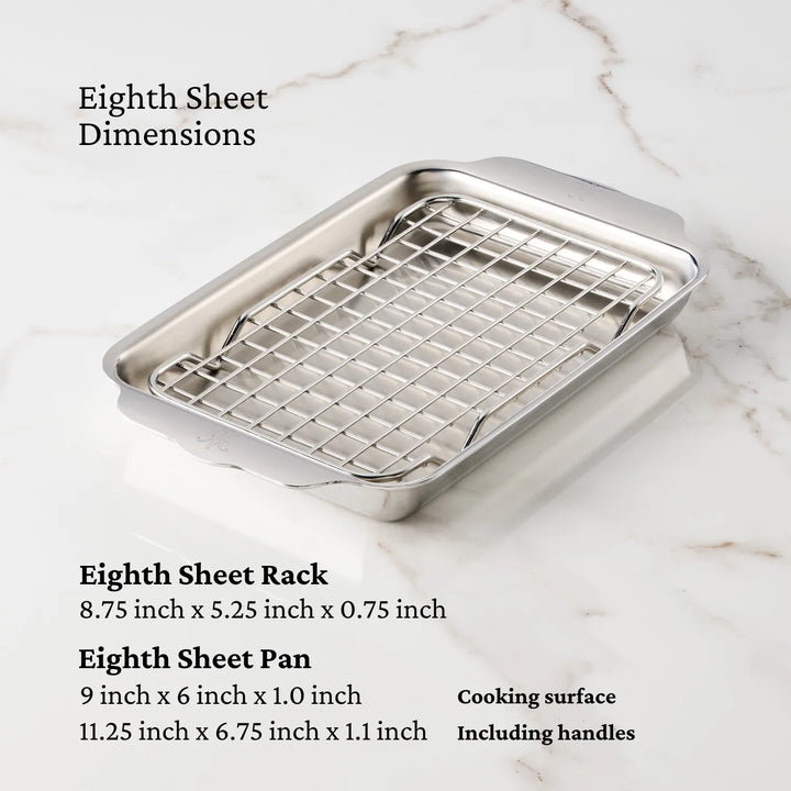 The Hestan Provisions OvenBond Tri-ply Mini Eighth Sheet Pan with Rack, featuring dimensions of 9x6x1.1 for the pan and 8.75x5.25x0.75 for the rack, is elegantly displayed on a light marble surface.