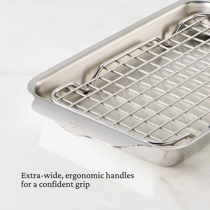 The Hestan Provisions OvenBond Tri-ply Mini Eighth Sheet Pan with Rack is a stainless steel roasting pan featuring a grid rack and extra-wide ergonomic handles for a confident grip. Perfect on a white marble surface, its versatile for all your baking and roasting needs.