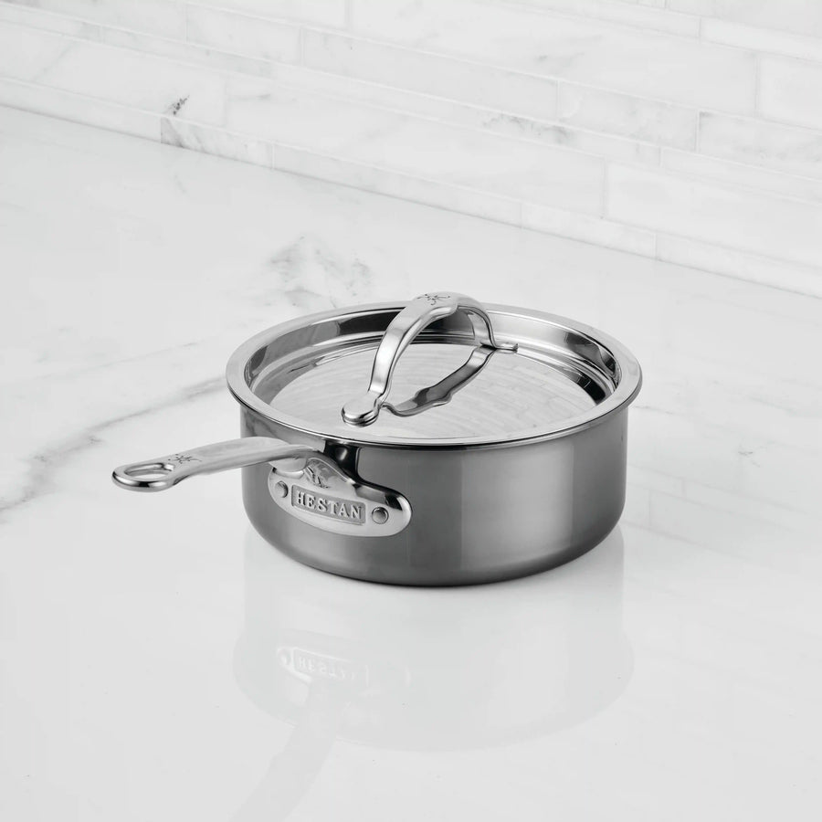 A NanoBond Titanium Saucepan with a matching lid sits on a white marble countertop, its shiny surface reflecting the light. The NanoBond brand is visible on the side, highlighting its advanced titanium technology.