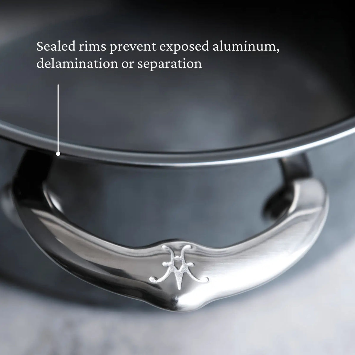 The Titanium Sauté Pans by NanoBond have a stainless steel handle with a logo, smooth finish, and secure attachment. Their sealed rims prevent exposed aluminum and delamination for durability, offering a sleek, modern look.