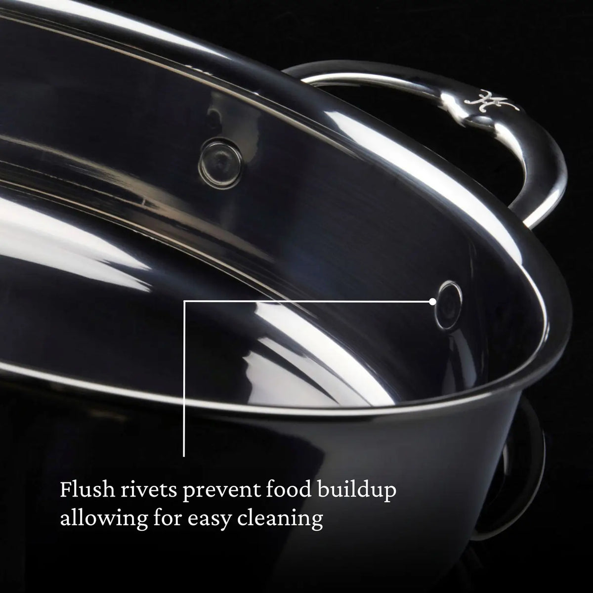 Close-up of a shiny Titanium Sauté Pan by NanoBond on a black background, featuring flush rivets for easy cleaning and food buildup prevention. The Hestan NanoBond technologys molecular titanium coating enhances durability and brilliance.