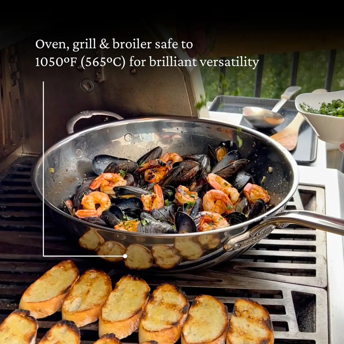 A skillet of mussels and shrimp sizzles on a grill, highlighting the NanoBond Titanium Chefs Pans perfection. Toasted bread crisps beside it. Text states, Titanium Chefs Pan is oven, grill & broiler safe to 1050°F (565°C) for brilliant versatility.