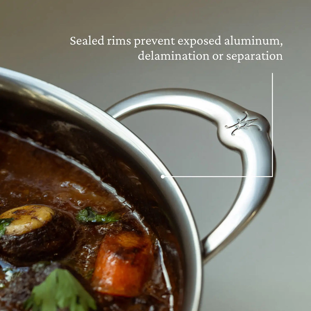 Close-up of a metal handle on the Titanium Dutch Oven, 5-Quart, filled with food like mushrooms, carrots, and herbs. A line points to the handle with text emphasizing sealed rims to prevent aluminum exposure, delamination, or separation in this NanoBond creation.