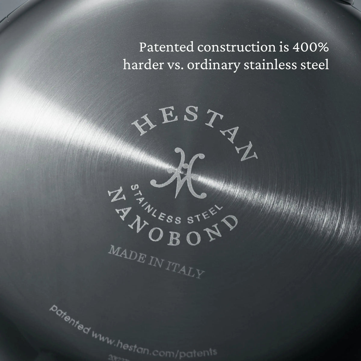 Close-up of the bottom of a NanoBond Titanium Stockpot, showing text: Patented construction is 400% harder vs. ordinary stainless steel. The NanoBond branding and website are visible.