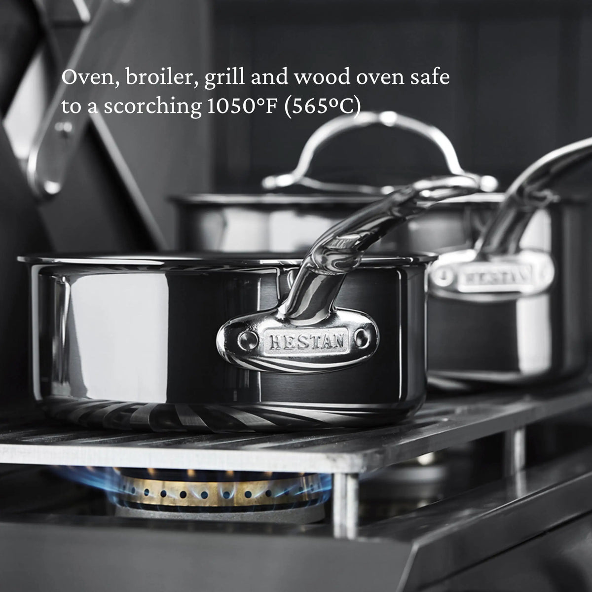 Two Titanium Stockpots by NanoBond sit on a gas burner with a blue flame. Text above states: Oven, broiler, grill, and wood oven safe up to a scorching 1050°F (565°C).