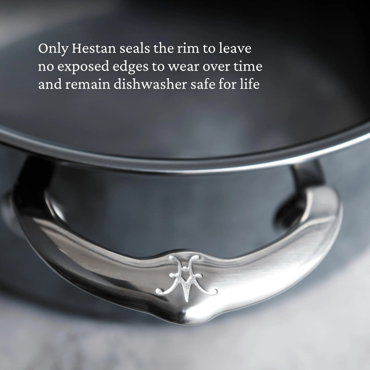 Close-up of a NanoBond Titanium Stockpot handle with engraved logo and part of the rim. Text above notes NanoBond seals the rim to prevent exposed edges, boosting durability and making it dishwasher safe for life.
