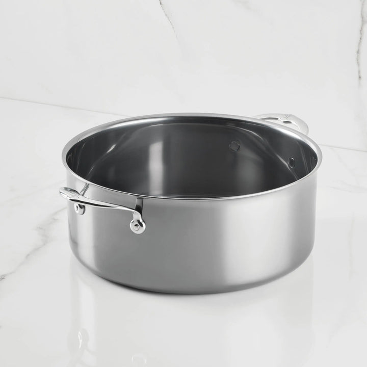 A NanoBond Titanium Rondeaus with dual handles sits on a white marble countertop, complemented by a white marble backsplash in the background.