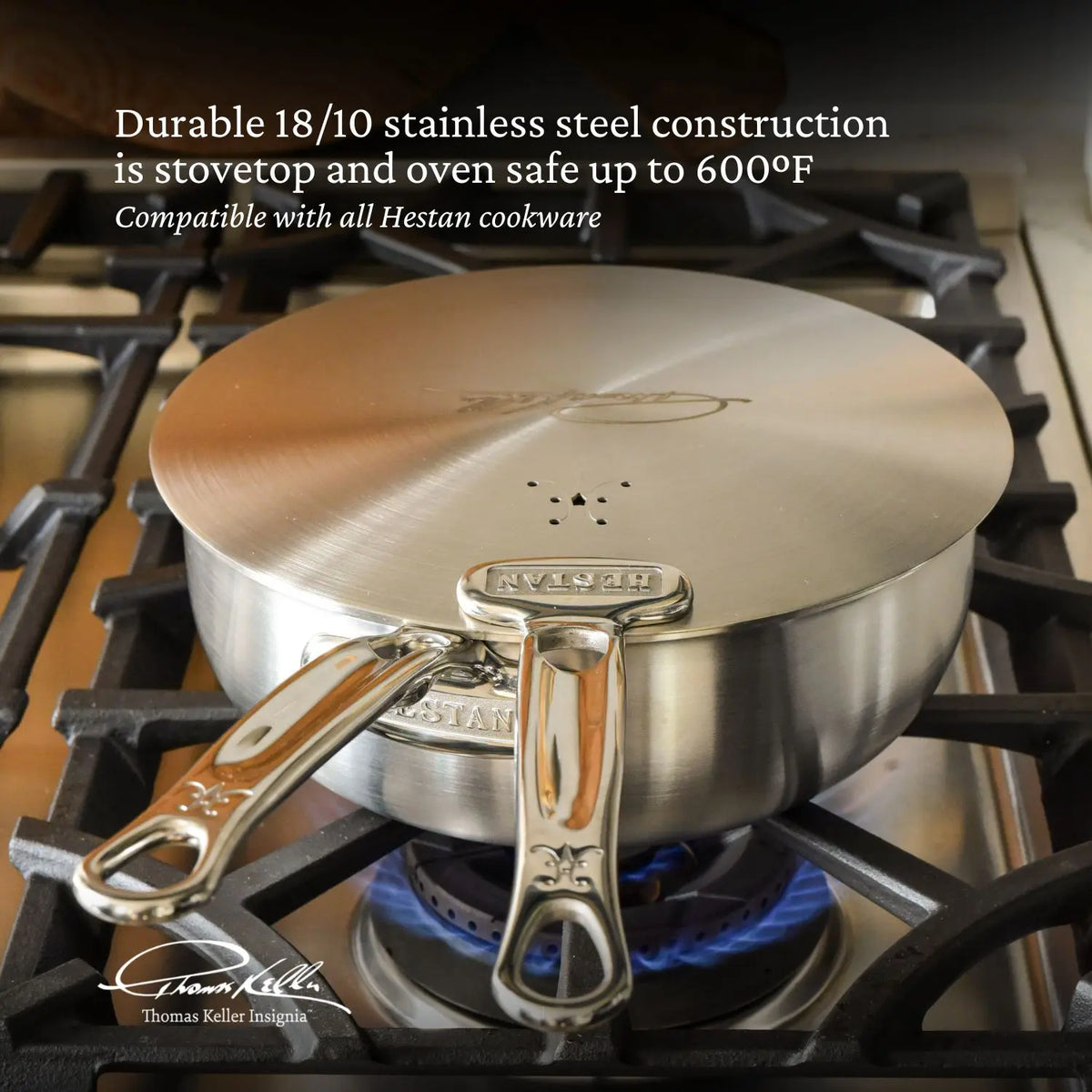 A Thomas Keller Commercial Clad Stainless Steel Universal Lid, made of 18/10 stainless steel, sits on a gas burner. It’s stovetop and oven safe up to 600°F, and compatible with Hestan commercial clad cookware.