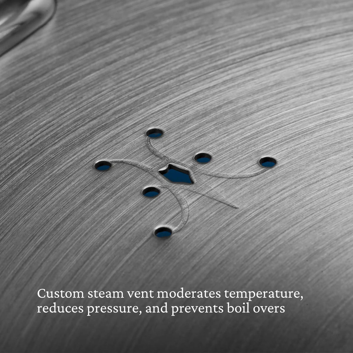 Close-up of the Thomas Keller Commercial Clad Stainless Steel Universal Lids highlights a custom steam vent with symmetrical holes and a brushed metal finish—perfect for eco-friendly cookware enthusiasts.