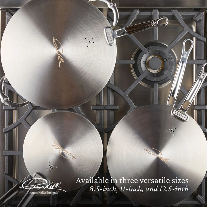 Three eco-friendly Thomas Keller Insignia stainless steel frying pans, sized 8.5, 11, and 12.5 inches with long handles, are on display on a stovetop. The text highlights their versatile sizes and compatibility with Commercial Clad Stainless Steel Universal Lids for convenience.