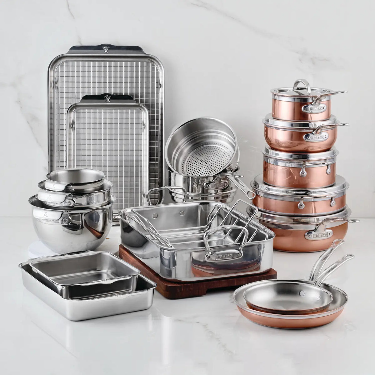 The CopperBond Copper Induction Set, 24-Piece—handcrafted in Italy—features stainless steel and copper pots, pans, mixing bowls, strainers, trays, and racks, all displayed on a white surface.
