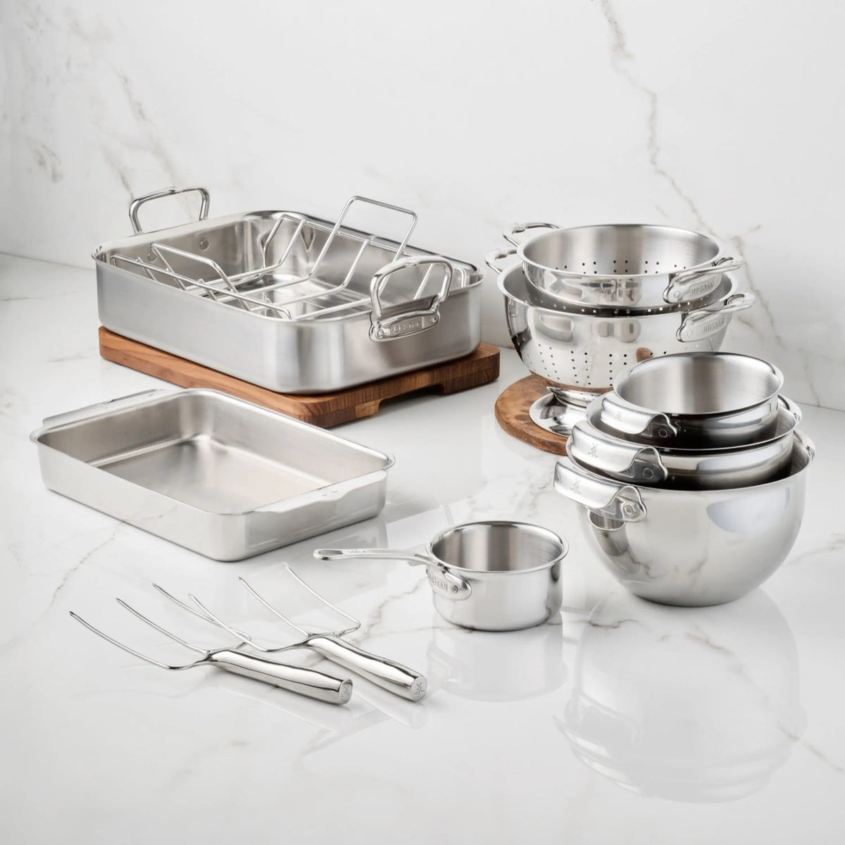 Hestan Provisions® Host and Roast, 10-piece durable stainless steel bakeware set including a roasting pan with rack, baking pan, colanders, mixing bowls, small saucepan, and two carving forks for holiday prep.