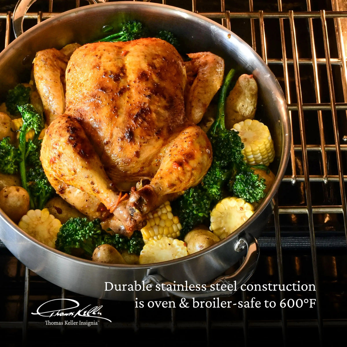 A whole roasted chicken sits in a stainless steel pan from the Thomas Keller Commercial Clad Stainless Steel 29-Piece Cookware Set, surrounded by broccoli, potatoes, and corn. Durable construction; oven safe up to 600°F.