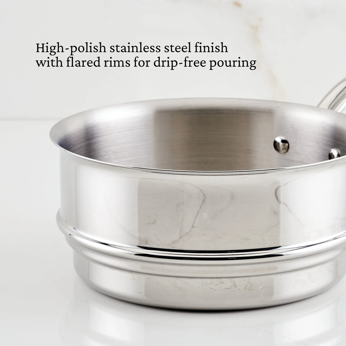 A close-up of the Thomas Keller Commercial Clad Stainless Steel 29-Piece Cookware Set with a high-polish finish and flared, drip-free pouring rim, highlighting premium features against a white background.