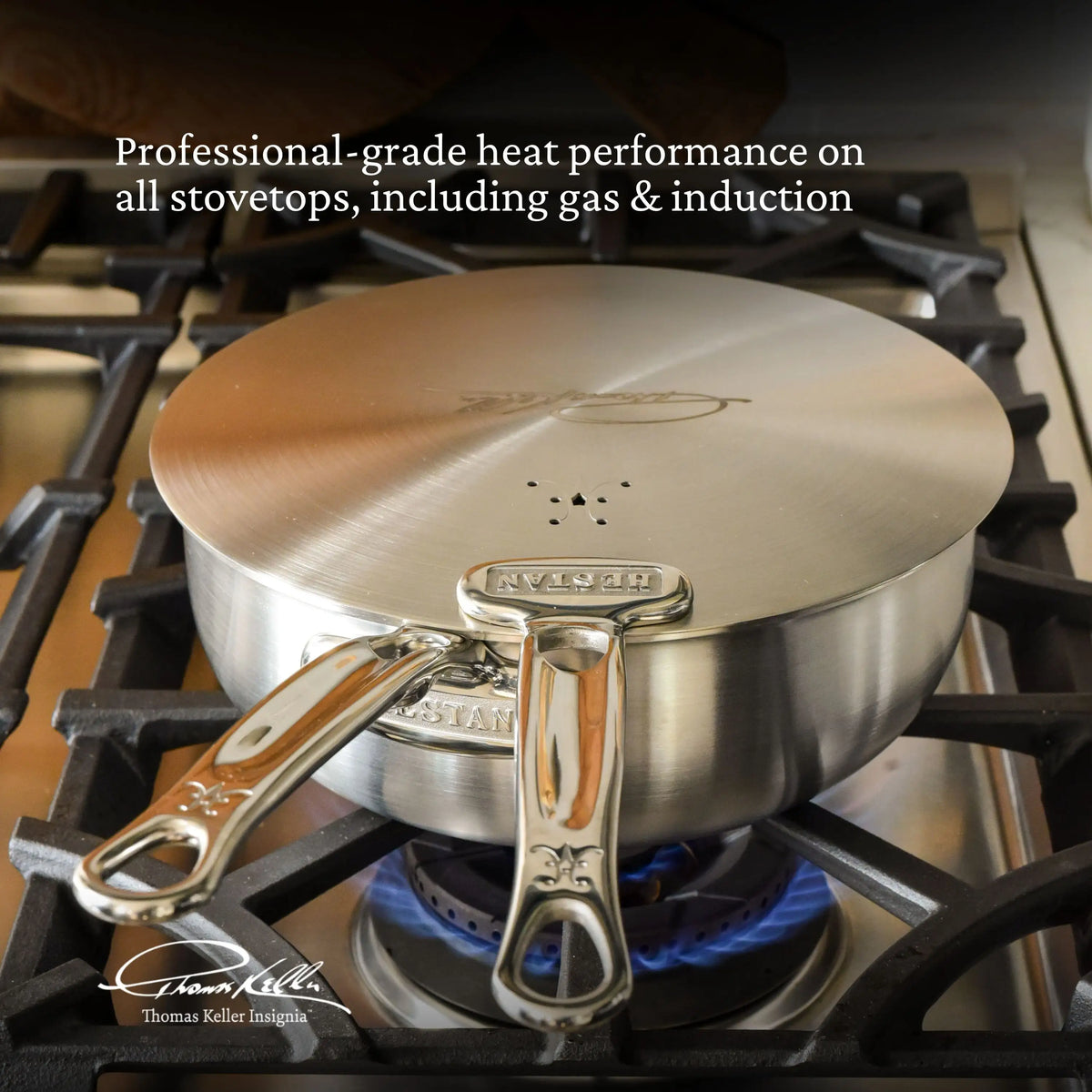 A saucepan from the Thomas Keller Commercial Clad Stainless Steel 29-Piece Set sits on a gas stove, blue flame visible. Text above: Professional-grade heat performance with Thomas Keller cookware on gas & induction stovetops.
