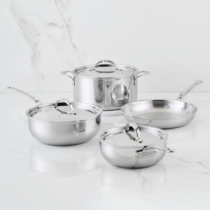 The ProBond® Luxe™ Polished Clad Stainless Steel Signature Set, 7-Piece, featuring cookware with matching lids, is arranged on a white marble surface.