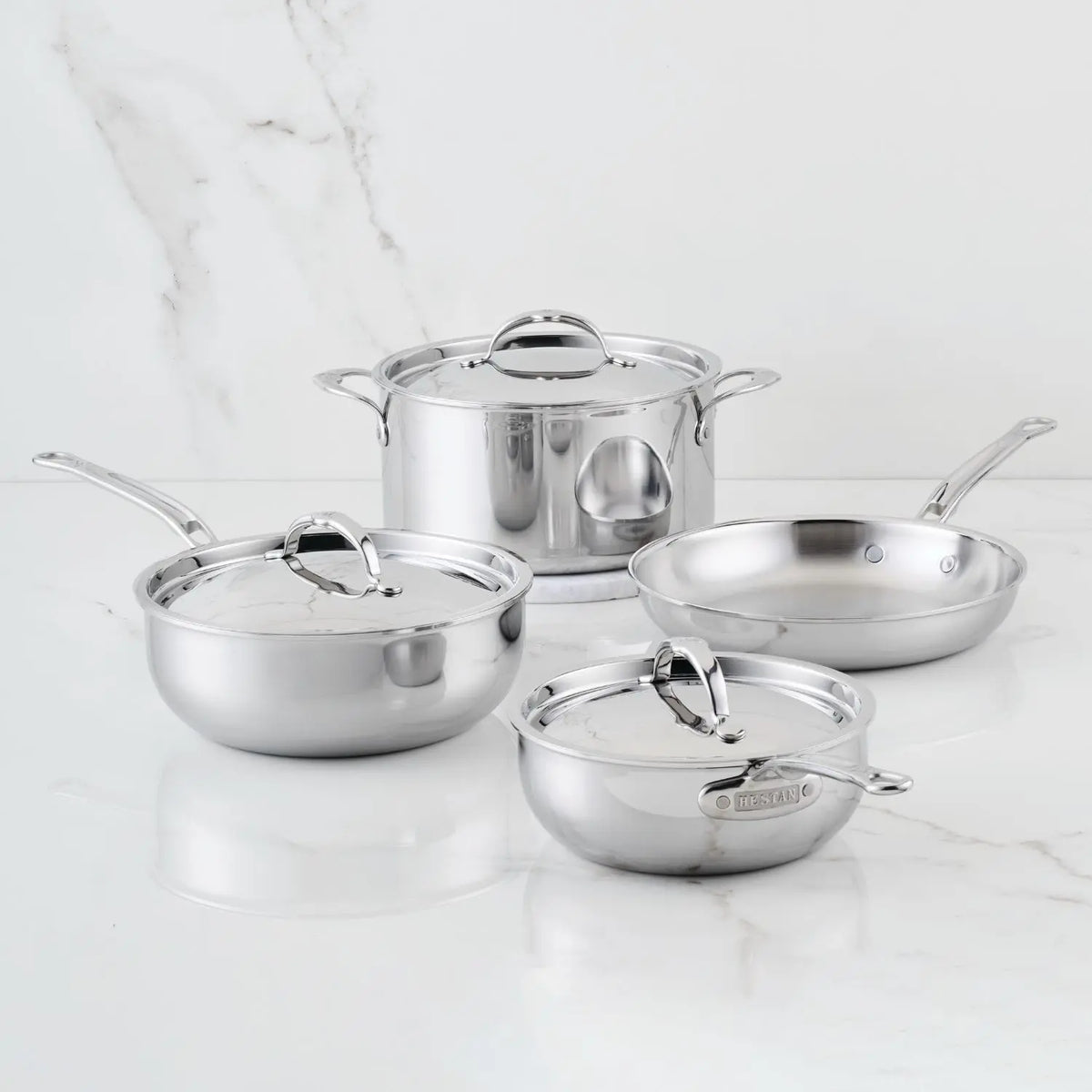 The ProBond® Luxe™ Polished Clad Stainless Steel Signature Set, 7-Piece, featuring cookware with matching lids, is arranged on a white marble surface.