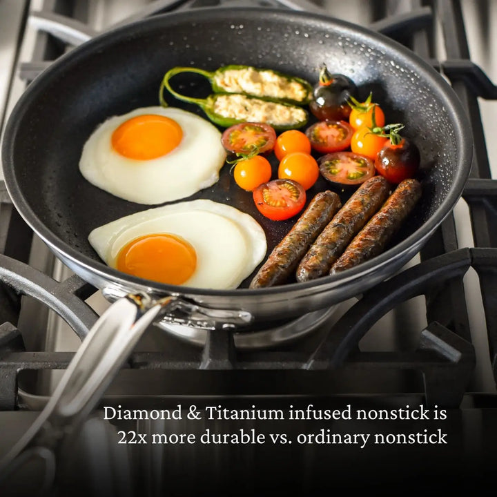 A nonstick frying pan on a stove displays two sunny-side-up eggs, cherry tomatoes, sausages, and stuffed peppers. The bottom text reads, Diamond & Titanium infused nonstick is 22x more durable vs. ordinary nonstick, highlighting the resilience similar to ProBonds Professional Clad Performance cookware.