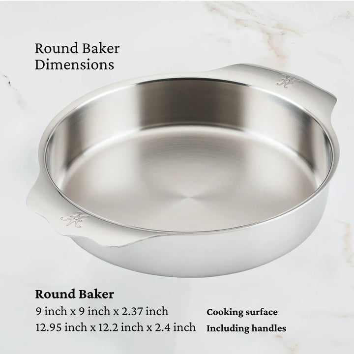 The Hestan ProBond Professional Clad Performance baking dish rests on a marble surface, featuring a tri-ply aluminum core. Its cooking surface is 9x9x2.37, and the handles extend to 12.95x12.2x2.4, adorned with subtle decorative elements.