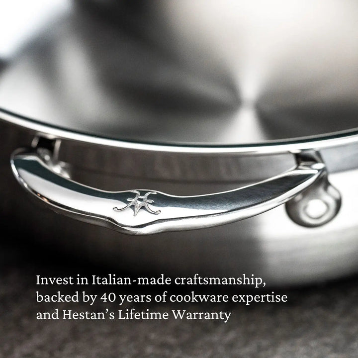 Close-up of a stainless steel pan handle with the ProBond logo. Accompanying text says, Benefit from Italian craftsmanship, 40 years of cookware expertise, and Hestan ProBond’s Lifetime Warranty. The Professional Clad Stainless Steel Braisers surface is blurred in the background.