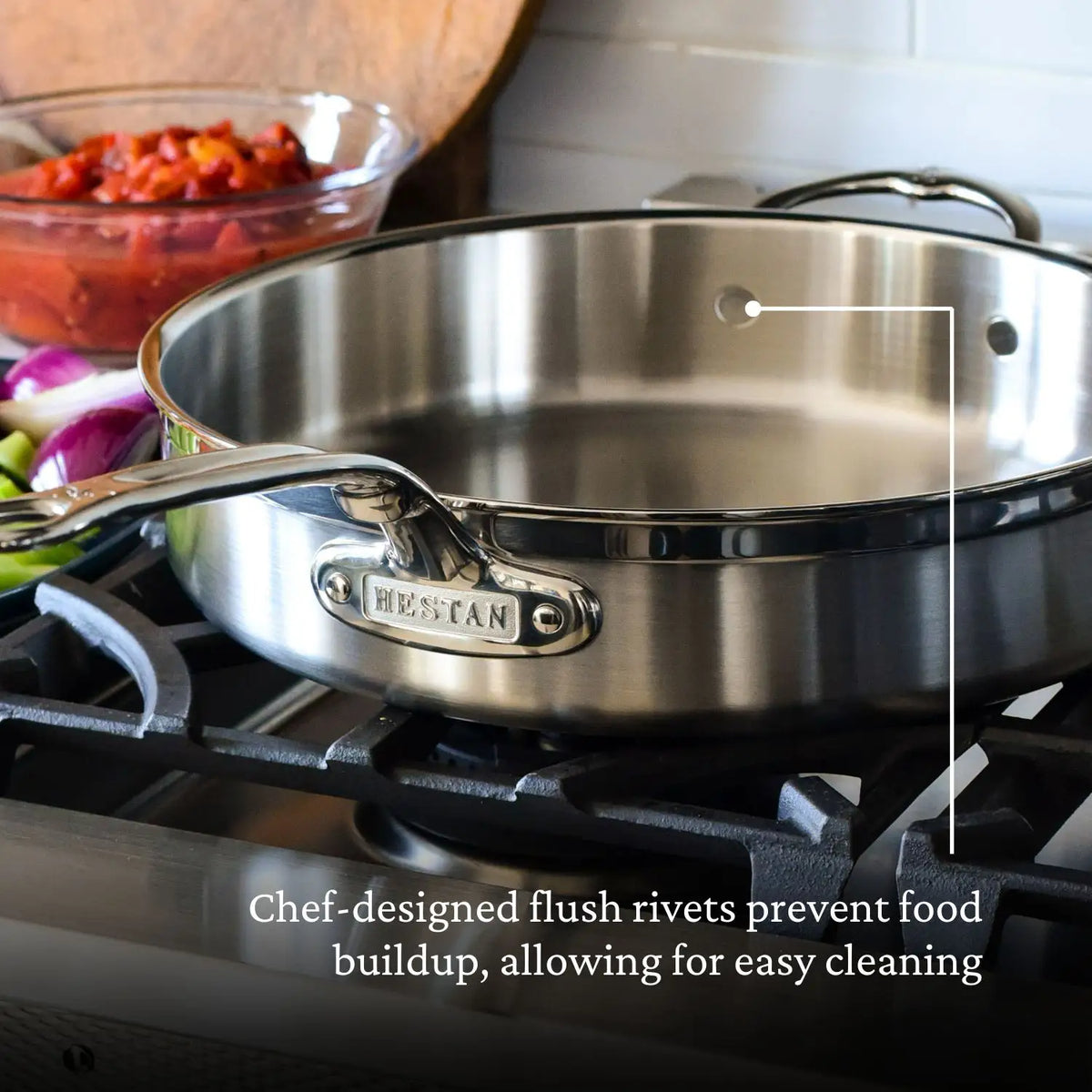 A ProBond Professional Clad Performance pan sits on a stove, highlighting chef-designed flush rivets inside that aid in effortless cleaning. Vegetables are visible in the background with text: Effortless cleanup.