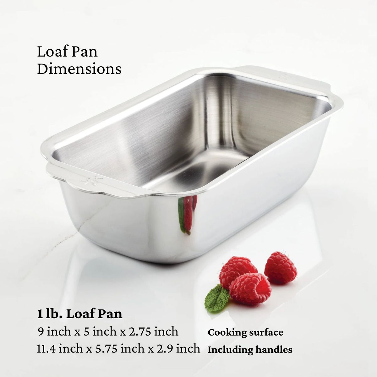 A Hestan Provisions stainless steel loaf pan from the OvenBond Tri-ply Gourmet Essentials 7-piece set sits on a white surface with three raspberries beside it. Text describes dimensions and the award-winning cooking surface of this top-tier kitchen gear.