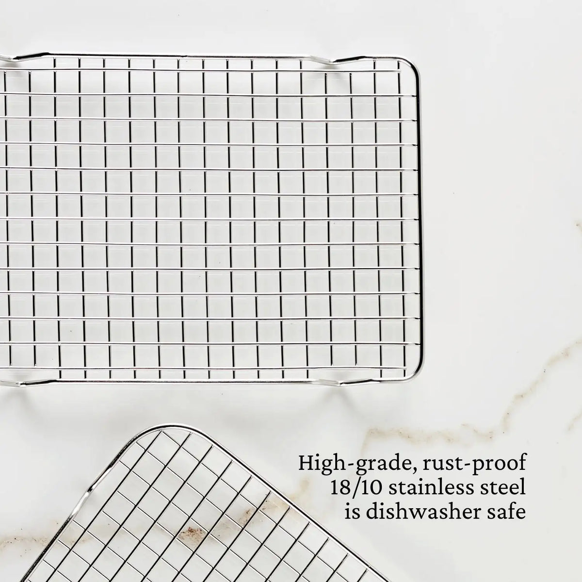 Two OvenBond Tri-ply Epicurean stainless steel cooling racks from Hestan Provisions are displayed on a white surface, highlighting their grid pattern with text stating, Durable, rust-proof 18/10 stainless steel bakeware thats dishwasher safe.