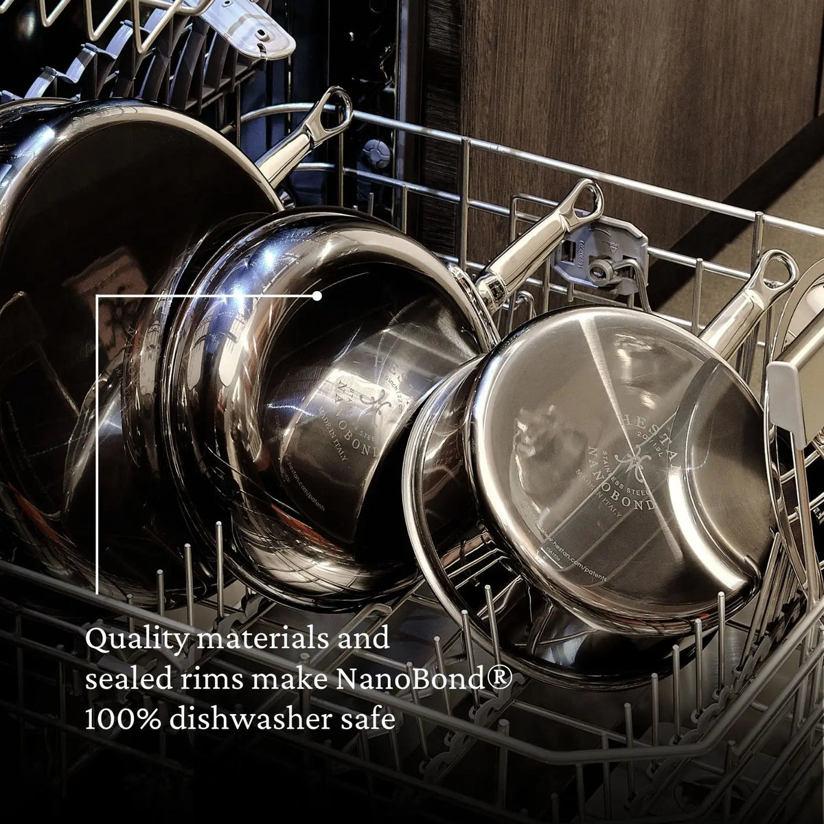 A stack of gleaming metal pots and pans from the NanoBond® Titanium x Tyler Florence Cookware Set, 41-Piece sits inside a dishwasher. Text on the image reads: Premium materials and seals—featuring Molecular Titanium—make NanoBond® 100% dishwasher safe.