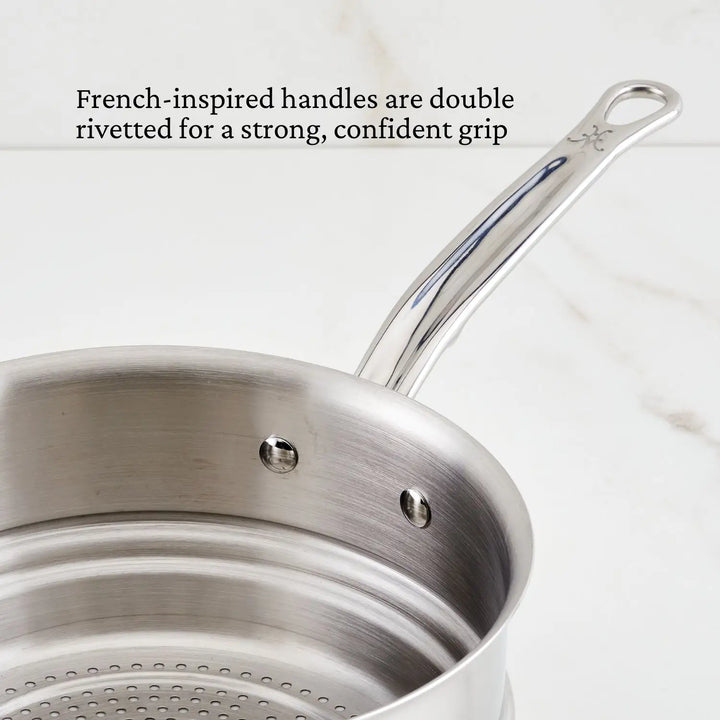 Displayed is a Thomas Keller Insignia Tri-Ply Stainless Steel steamer insert from the Commercial Clad set, featuring small bottom holes for steaming and a strong, double-riveted handle that ensures an excellent grip.