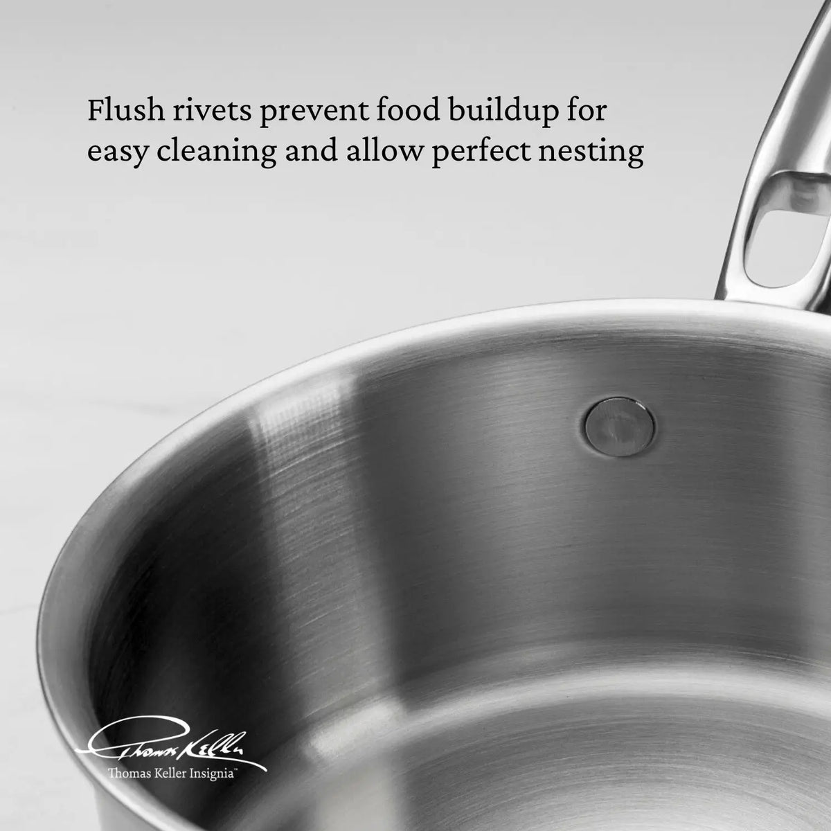 A close-up of the Thomas Keller Commercial Clad Stainless Steel 11-Piece Cookware Set shows a flush rivet, with text explaining it prevents food buildup and allows perfect nesting. The signature and logo highlight this eco-friendly, thoughtfully designed cookware.