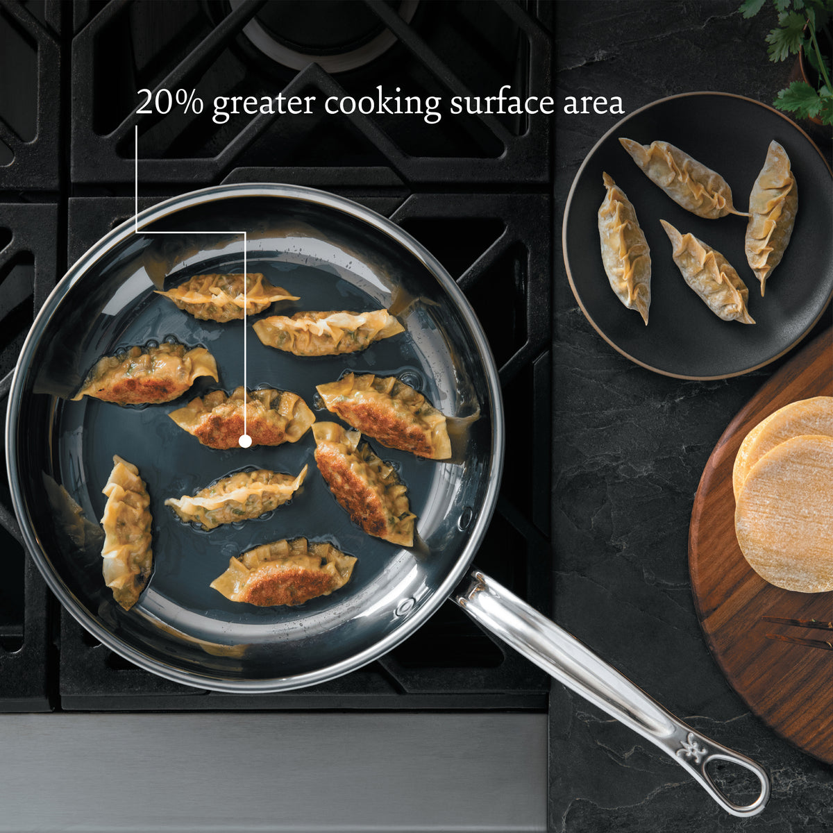 A NanoBond Titanium Induction 4pc Cookware Set sizzles with dumplings on the stovetop. Nearby, Italian handcrafted cookware presents dumplings on a black plate, and a wooden board holds uncooked ones. The product boasts a 20% greater cooking surface area.